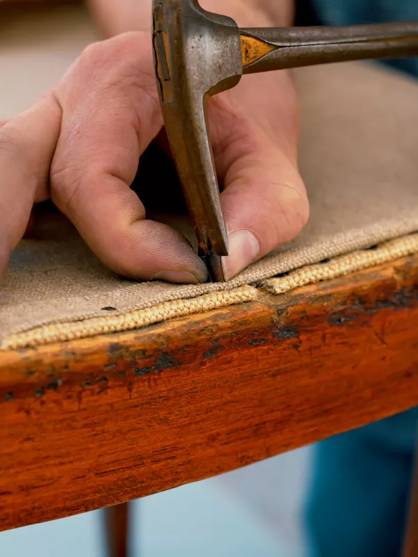 Bild zeigt Alexander bei der Arbeit beim Neubespannen eines Stuhles